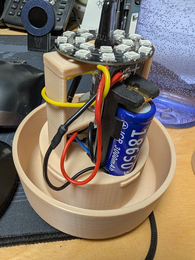 The insert with its cover off: the LED ring on top, an 18650 cell and wiring on the printed frame
