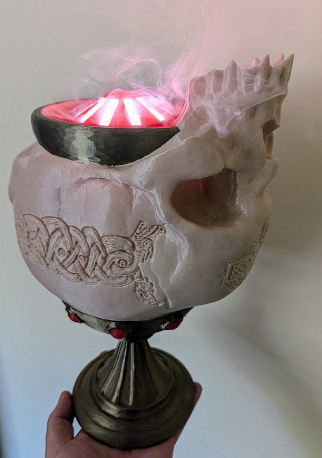 The finished chalice: a carved skull goblet on a metal stem, red-lit fog rising from the bowl